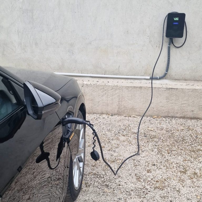 Installation borne de recharge Haute-Garonne Voiture électrique en charge, câble connecté à une borne murale.